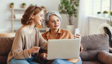 Mother and daughter using computer to bank online